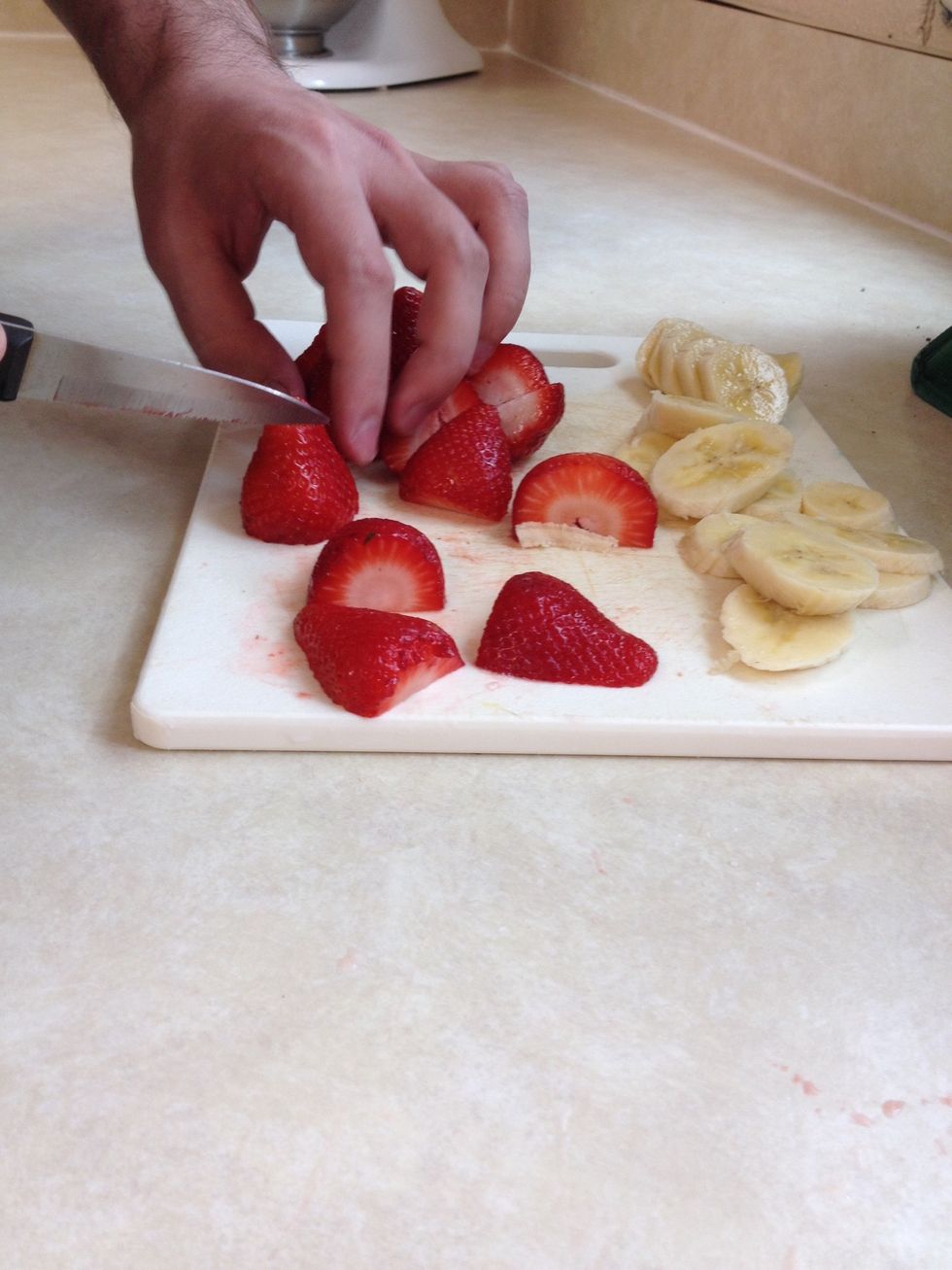 Once the fruit is rinsed, proceed by chopping the strawberries, banana, and apple.