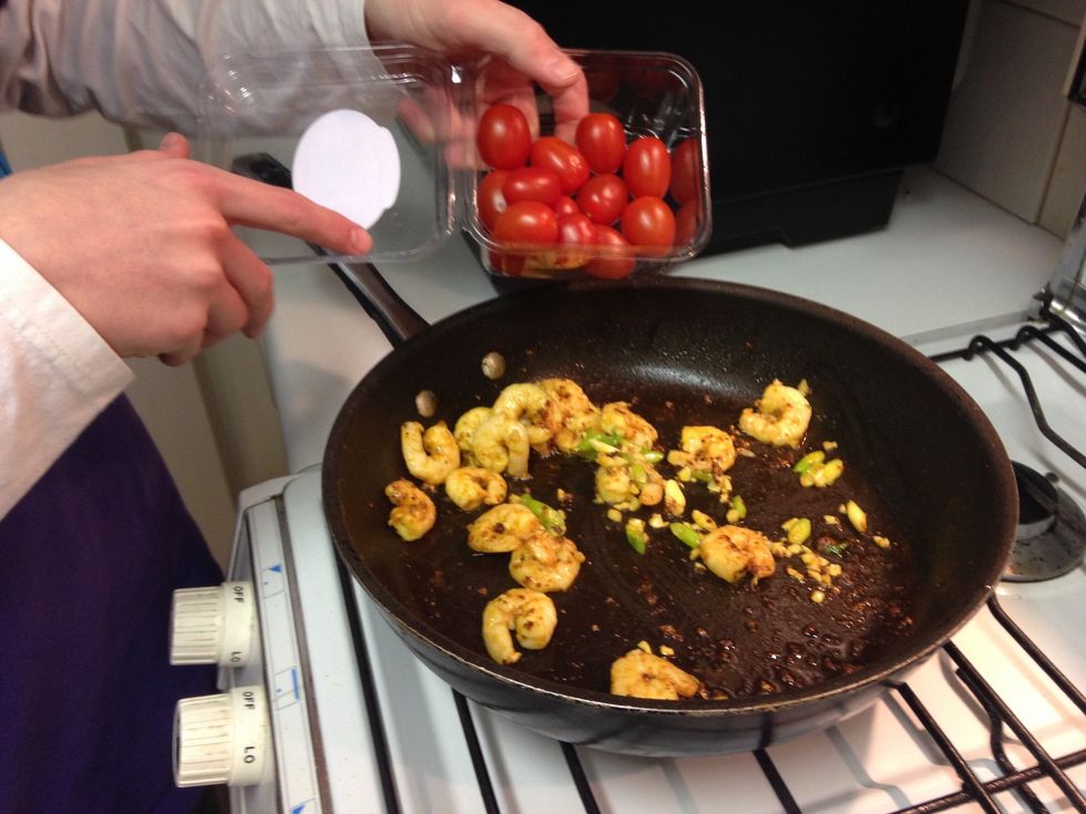 Once the garlic and spring onions have fried off a little bit and add a punnet of baby tomatoes.