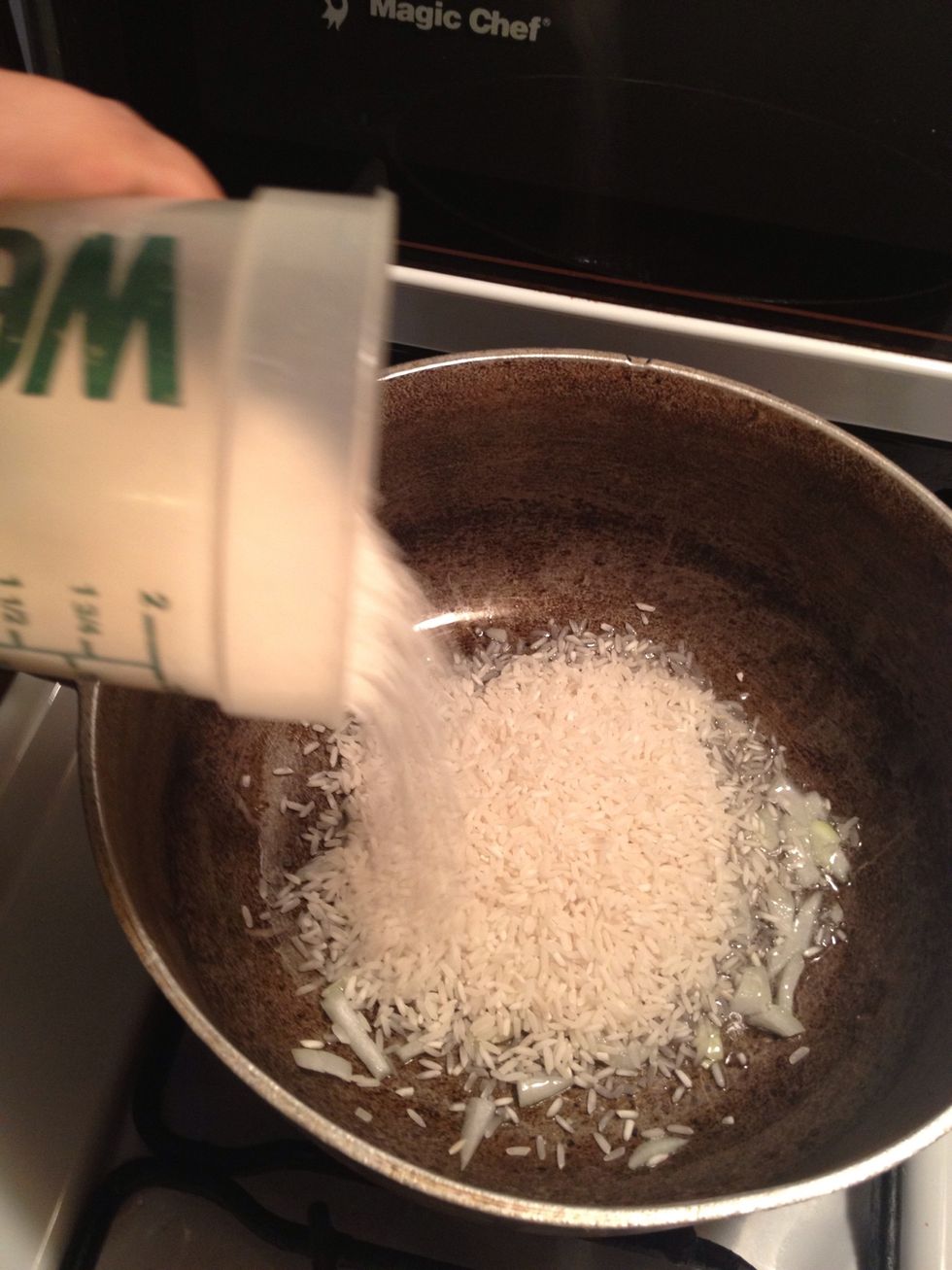 Once the onion begins to cook and the oil is hot, add the 2 cups of rice.