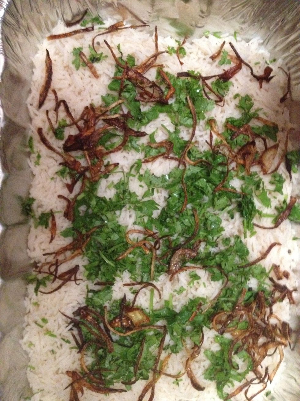 Once the rice is 80% done strain it and start assembling everything. I am using an aluminum dish. Add some rice and then cilantro then the fried onions