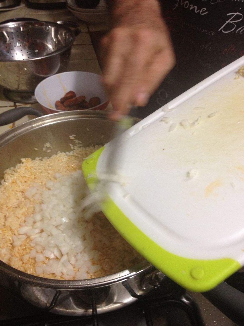 Once the rice is a bit looser and all painted orange, add the onion.