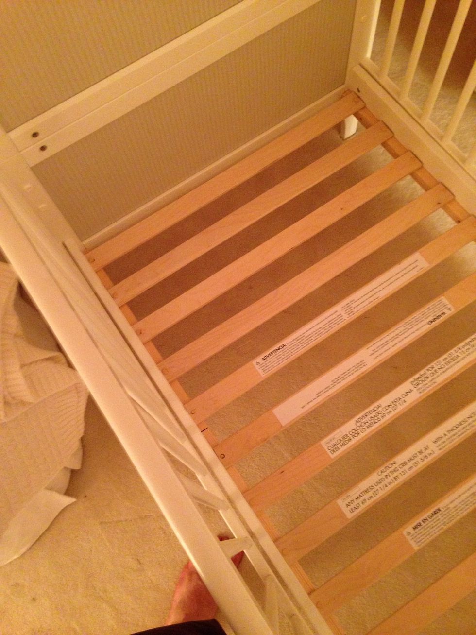 Once the sides are on, it's time to attach the bottom part. First, fit it into the bed frame and lower it to the floor. Make sure the exposed wooden slat things are facing up.