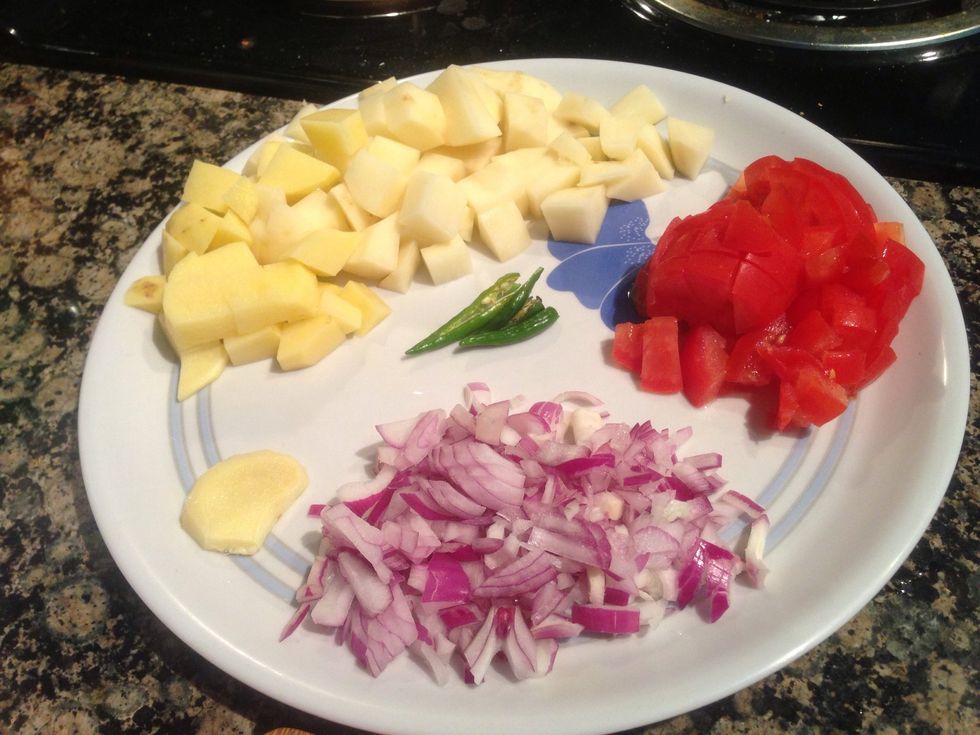 Once the soya chunks are resting off the heat, chop your vegetables as shown in the picture. Take a thick slice of ginger so it can be grated easily in the preparation. Cut small potato cubes.