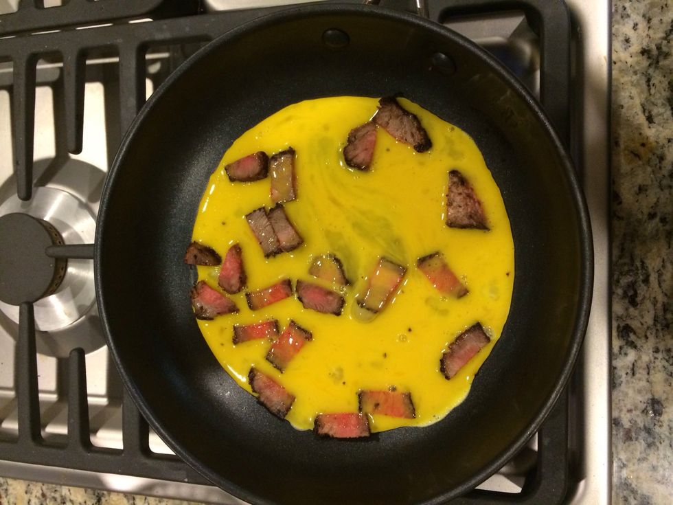 Once the steak is warm, add the eggs