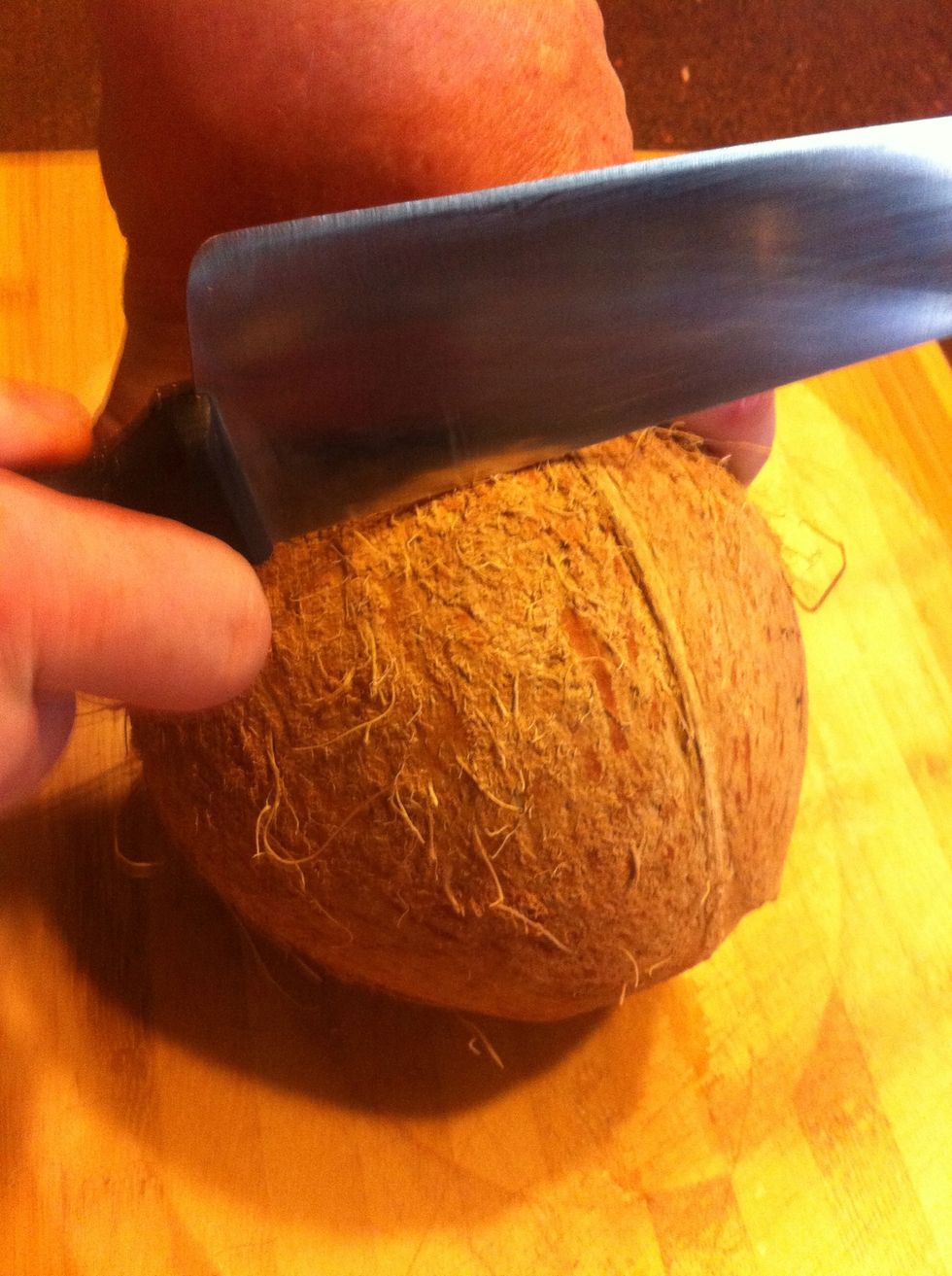 Once the water is drained, using the BACK of a chef's knife, firmly tap all around the coconut in a circle.