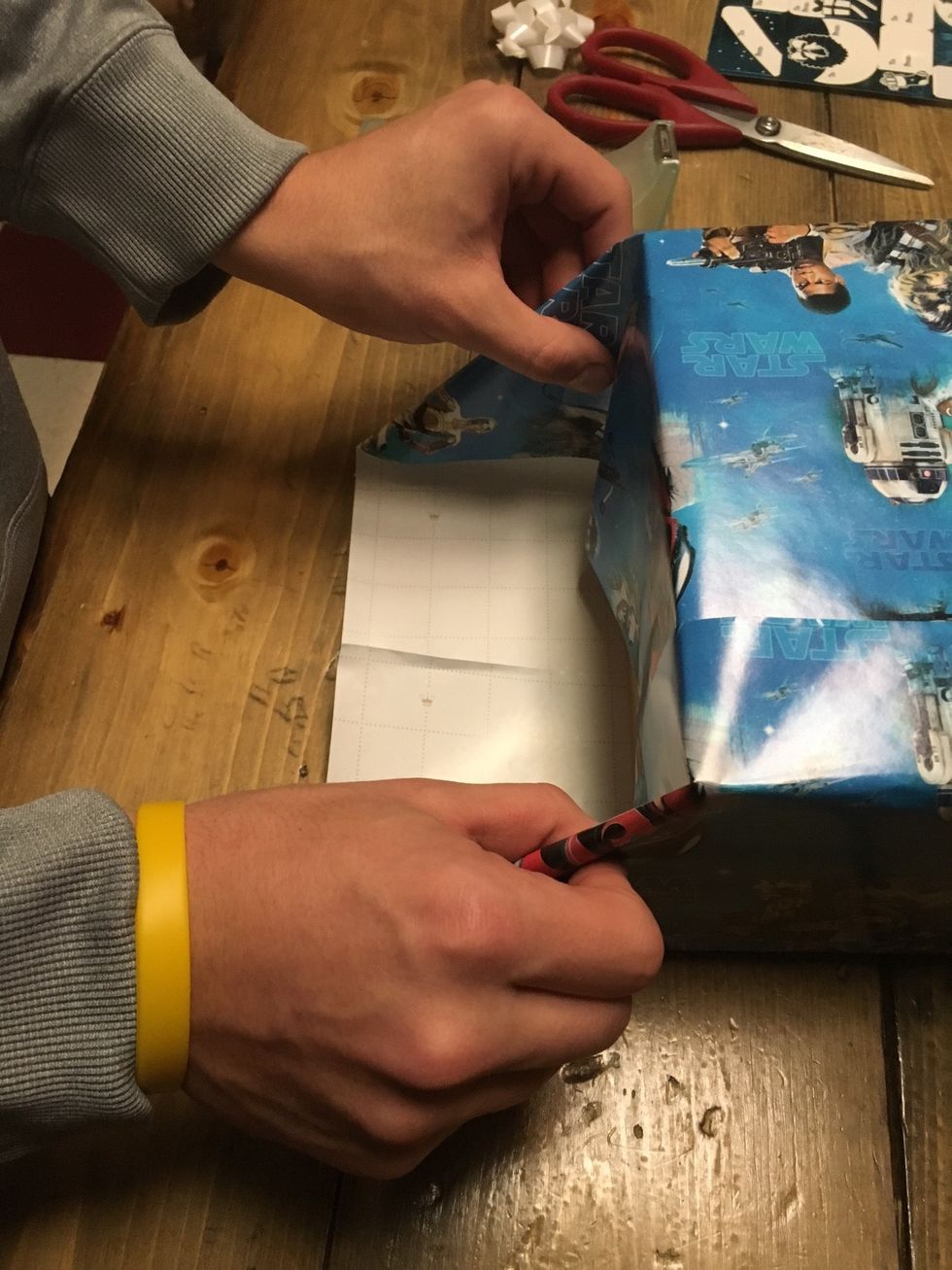 Once the wrapping paper is folded down, crease the edges on each side.