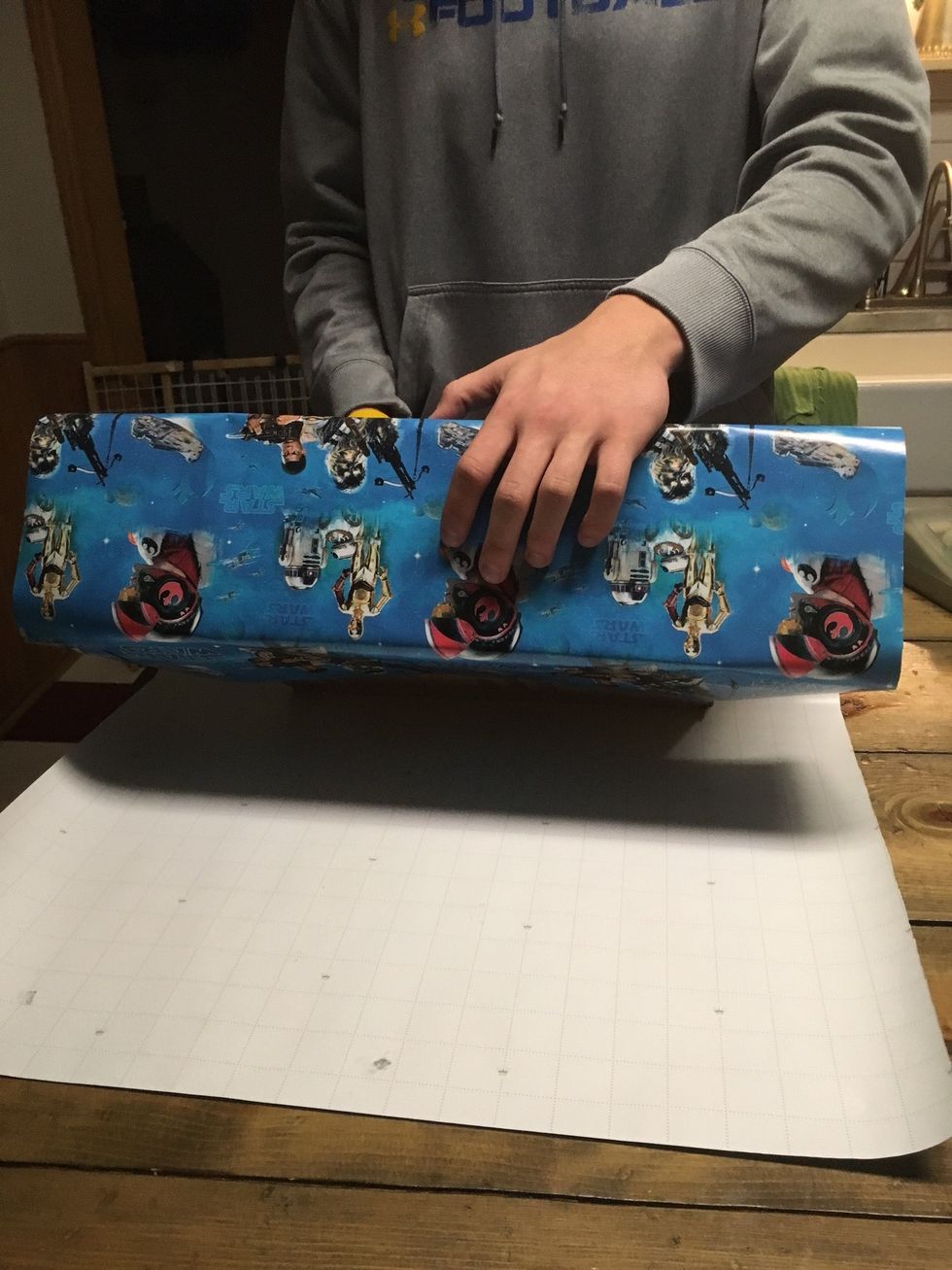 Once the wrapping paper is in place and taped, roll the box away from you until you run out of wrapping paper.