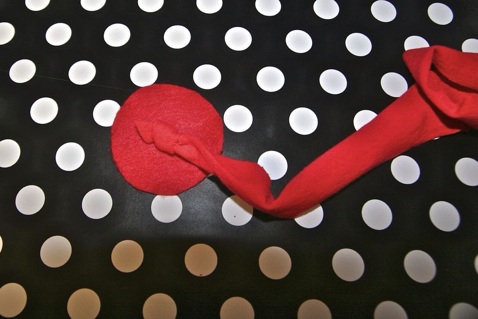 Once you cut out the circle.. Now it's time to wind your strip. 1.Begin by tying a knot on the tip of the strip 2.Add hot glue to the center of the circle 3.place knot on glue 4. Begin to twist strip