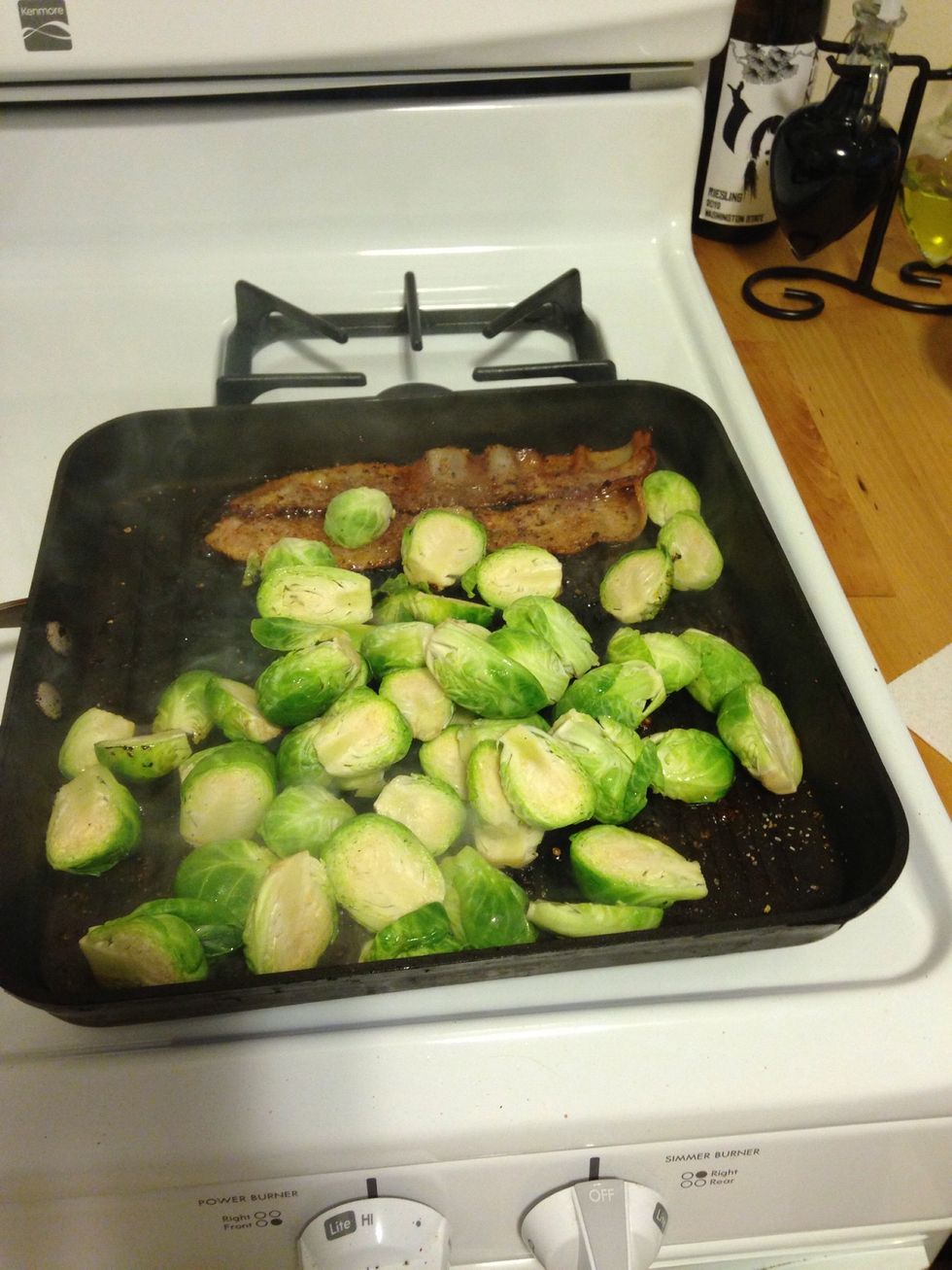 Once you flip your bacon, add the Brussels sprouts to the pan. It works best if you put the flat area on the pan so it can soak up delicious bacon grease.