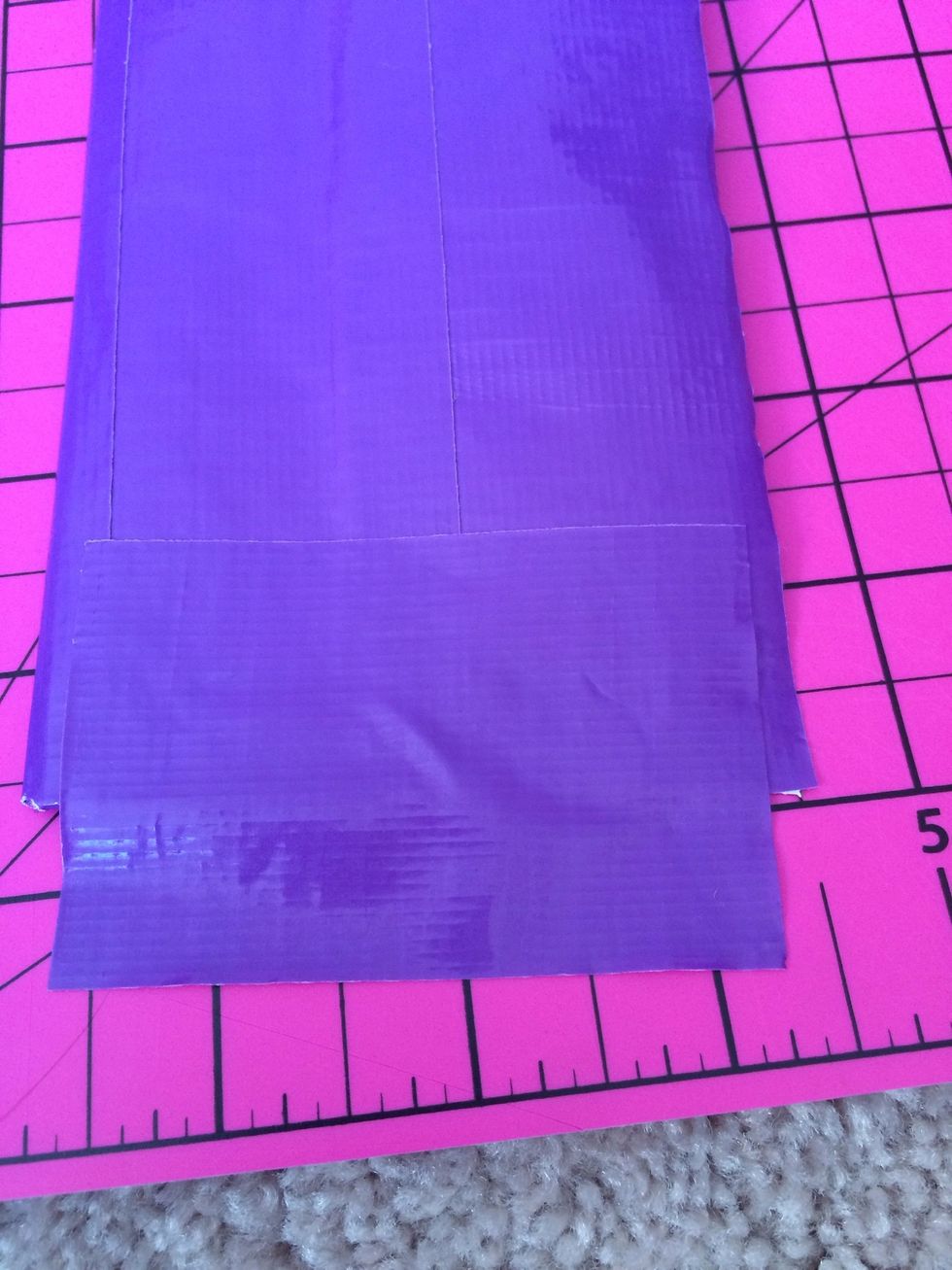 Once you have the sheet of duct tape folded into a rectangle, cut a 3 inch piece of colored duct tape and place half of the 3 inch piece on one side. Fold it over to the other side.