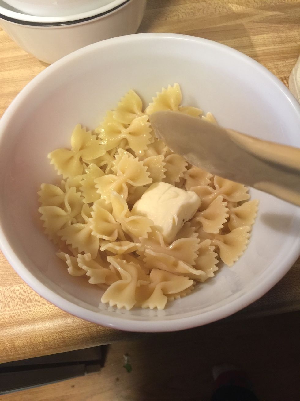 Once you're noodles are cooked drain them and put them in a bowl then add the butter I'm using about a tablespoon or so of butter for about a cup of noodles