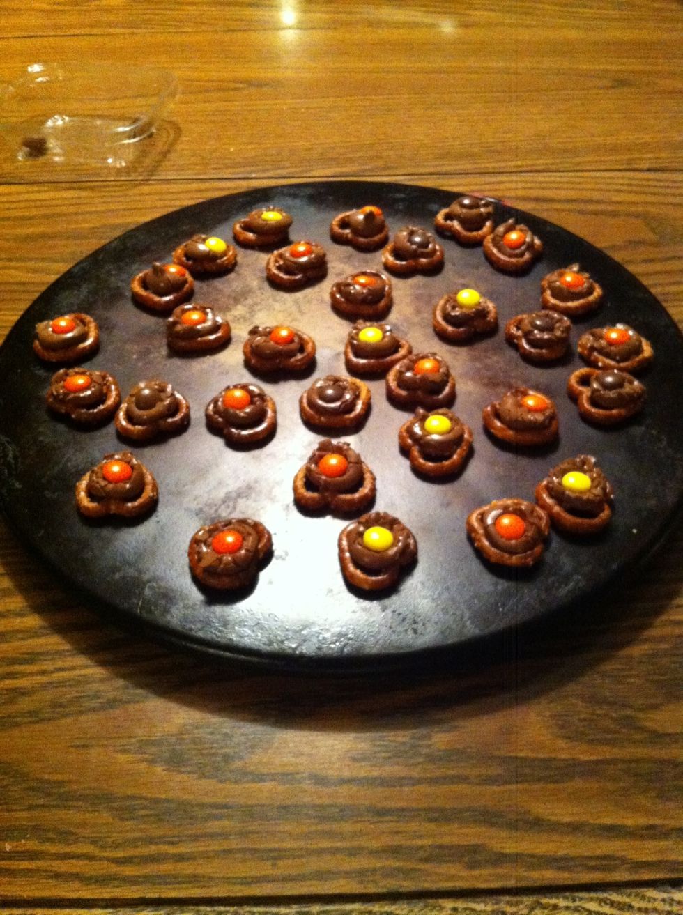 Once you take the pretzels out of the oven press the Reese's pieces carefully into the softened chocolate.