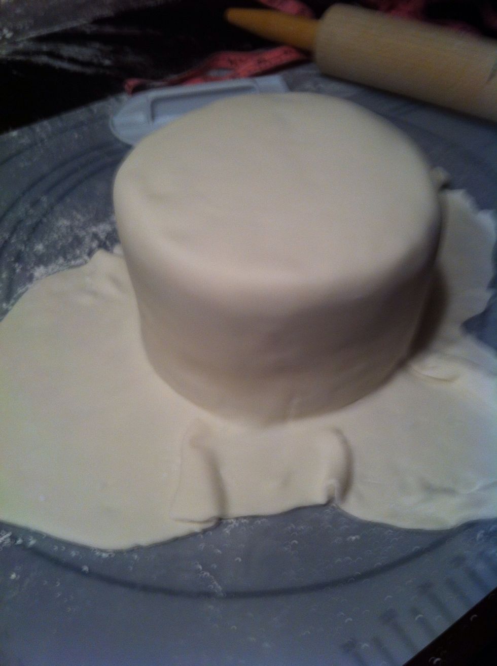 Once you've rolled the fondant to the size you need, roll it across the cake. There are two ways to do this. You could roll it across the rolling pin or throw it across your arm.