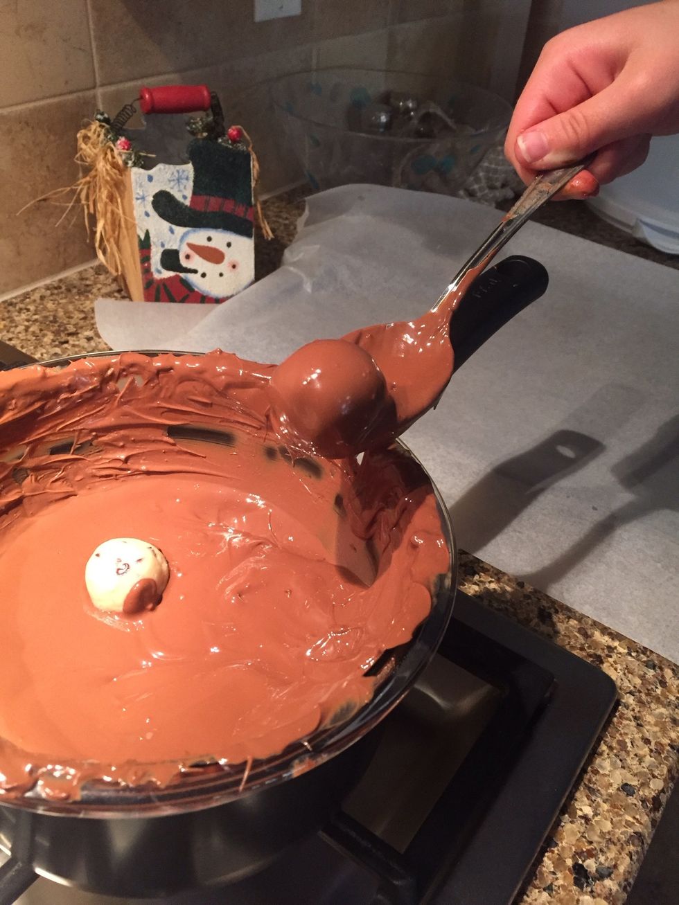 Once your chocolate is ready you can take the dough balls and use a spoon to dip them into the chocolate and roll them around until all sides are covered.