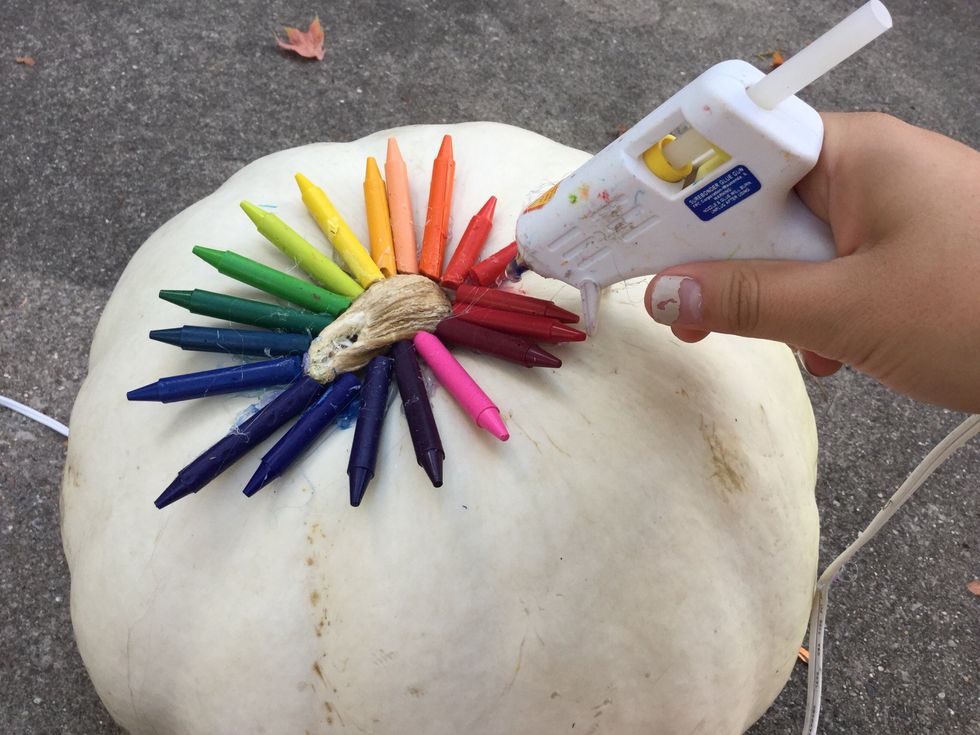 Once your hot glue gun is warmed up, you can glue half of your crayons around the stem of the pumpkin. Let it cool for about 5 minutes.