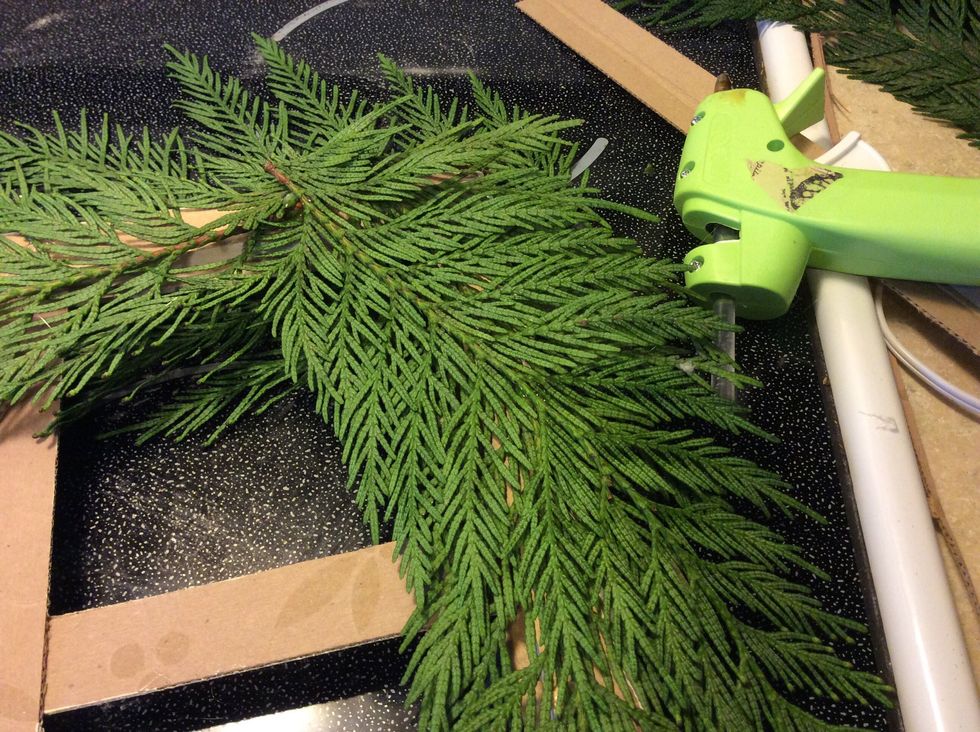 Once your window is distressed to your liking, place frame face down and arrange cedar clippings in the top right corner. Using hot glue, adhere to the backside of window.