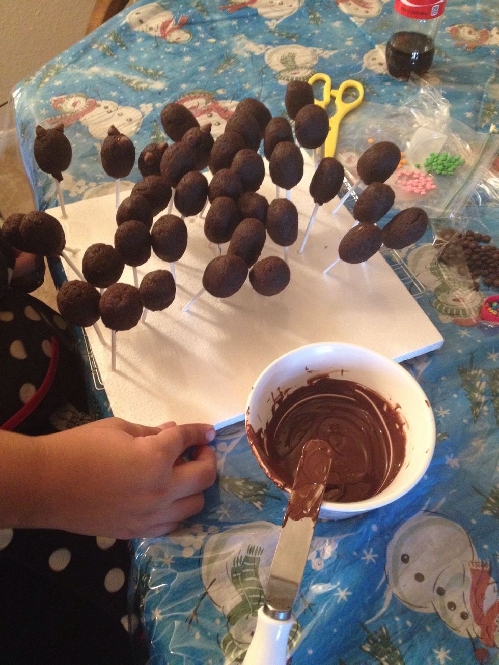 One at a time, dip about 1/2 inch of the tip of a lollipop stick into the melted candy coating, and insert the stick straight into the pointed tip of the balls, pushing it no more than 1/2 through.