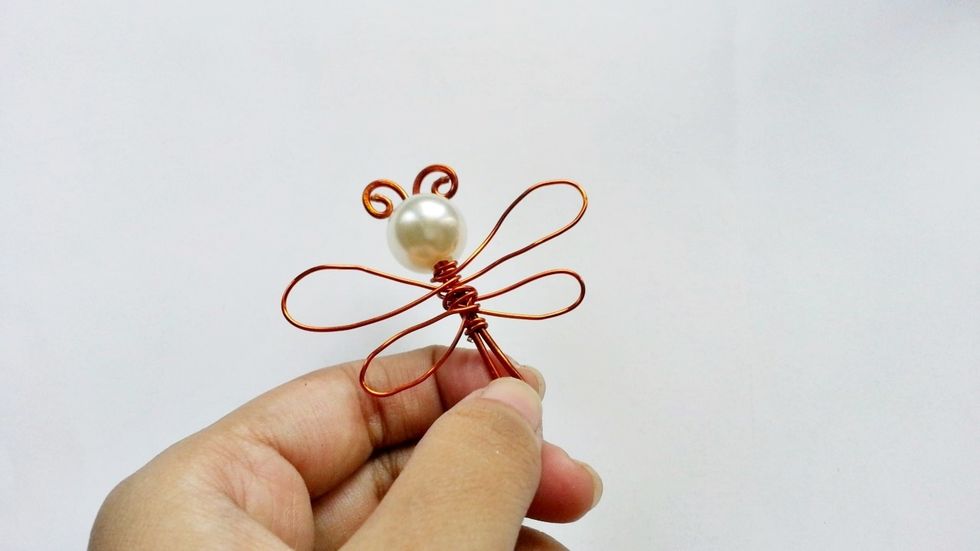 One by one make the 4 wings of the dragonfly, creating the upper wings first and then the lower wings. Wrap the remaining wire around the body part.