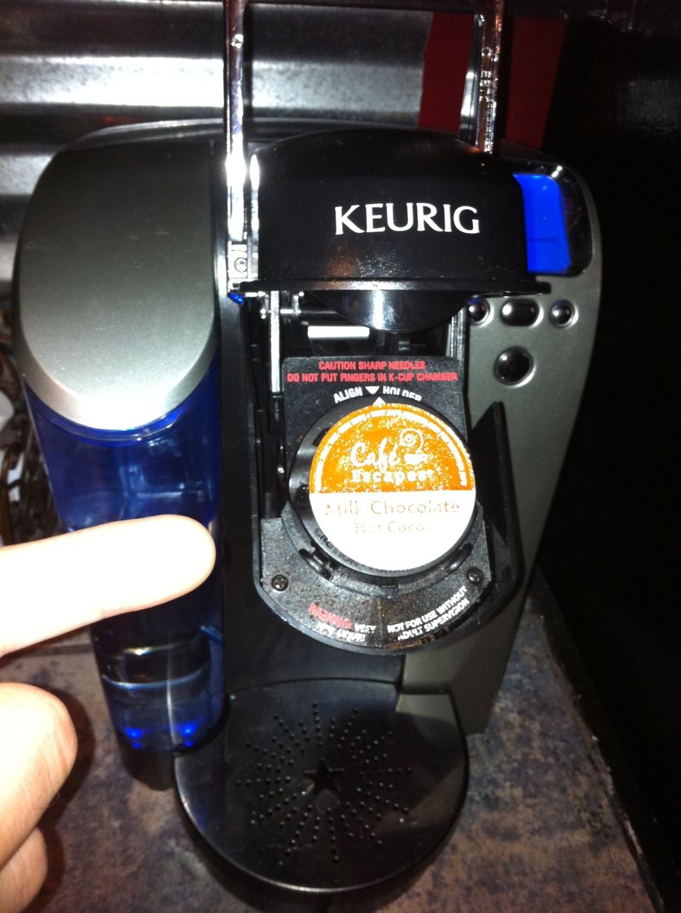 Open and place a hot chocolate single serving cup inside and close lid