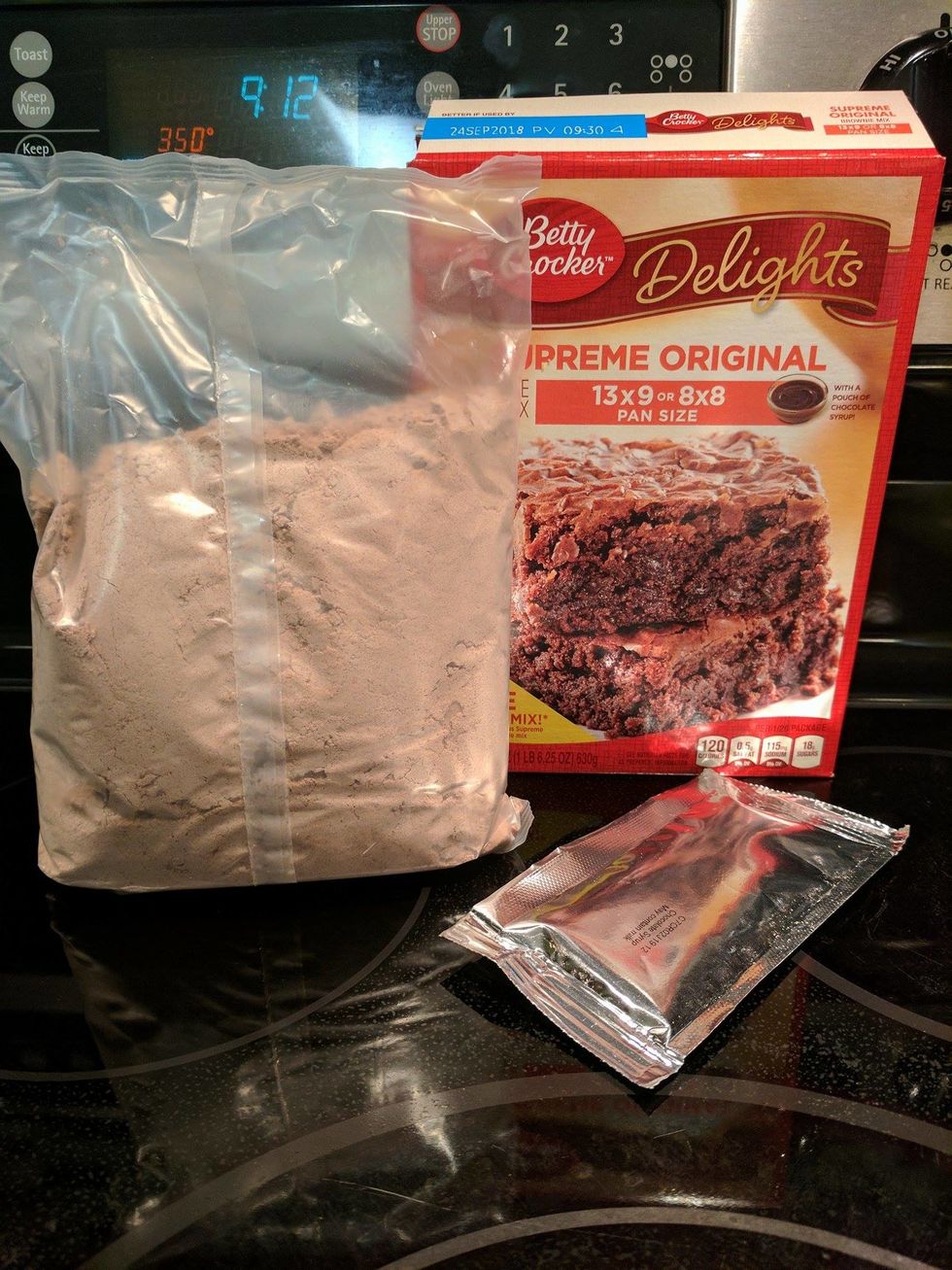 Open the Betty Crocker Supreme Original Delights Brownie Mix box and remove the dry brownie mix bag and the chocolate syrup pouch.