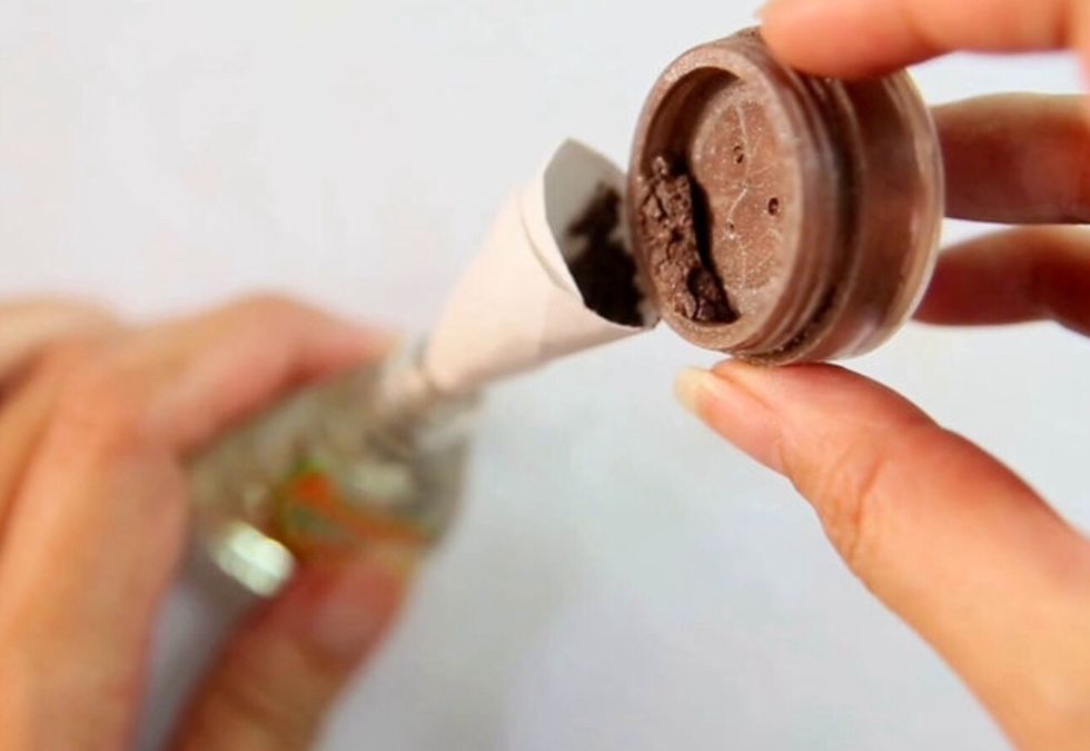 Open the bottle of clean nail polish, position the funnel over the top and pour in the eyeshadow. And if you have some glitter, add that too for a sparkly look.