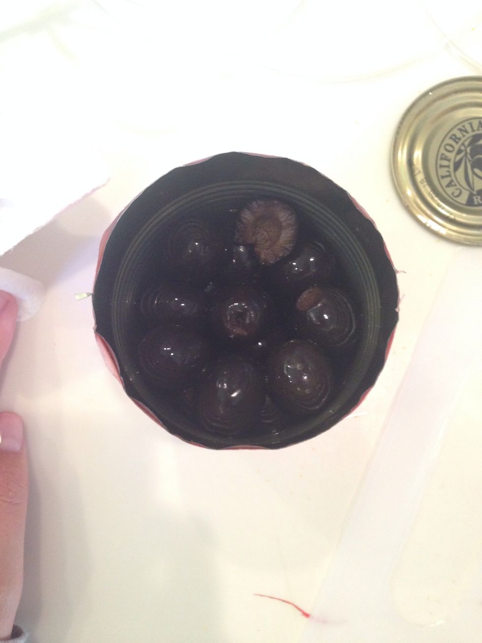 Open the can of olives and drain the juice in the sink