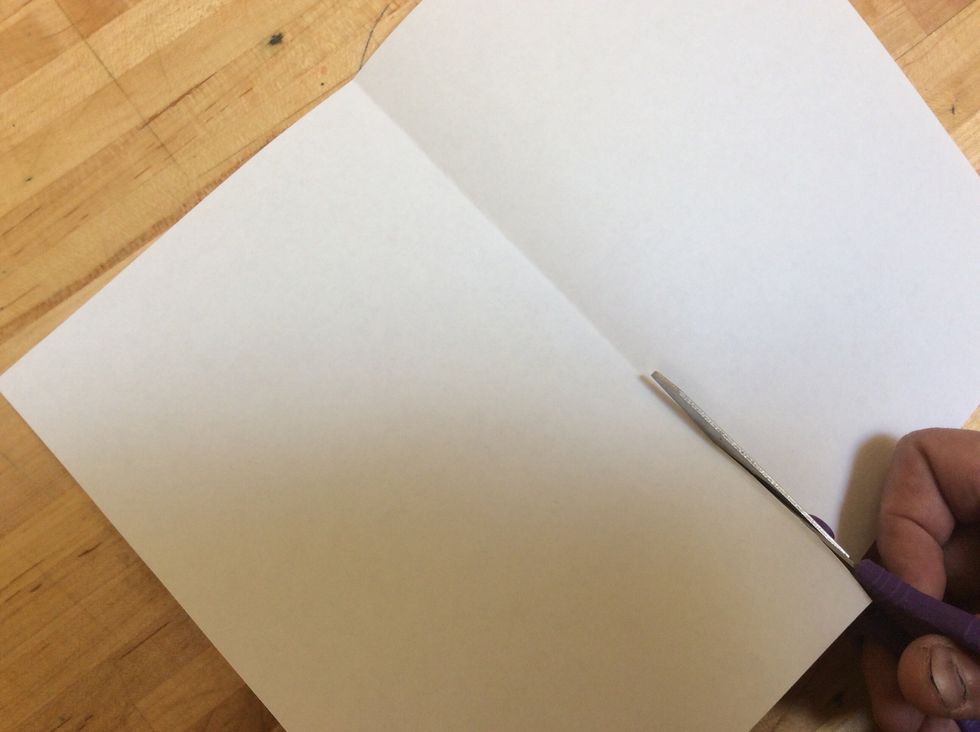 Open the paper and cut it in half, cutting a straight line along the fold. We now have two pieces. One piece will be used for the front of the cover, and one piece will be use for the back.
