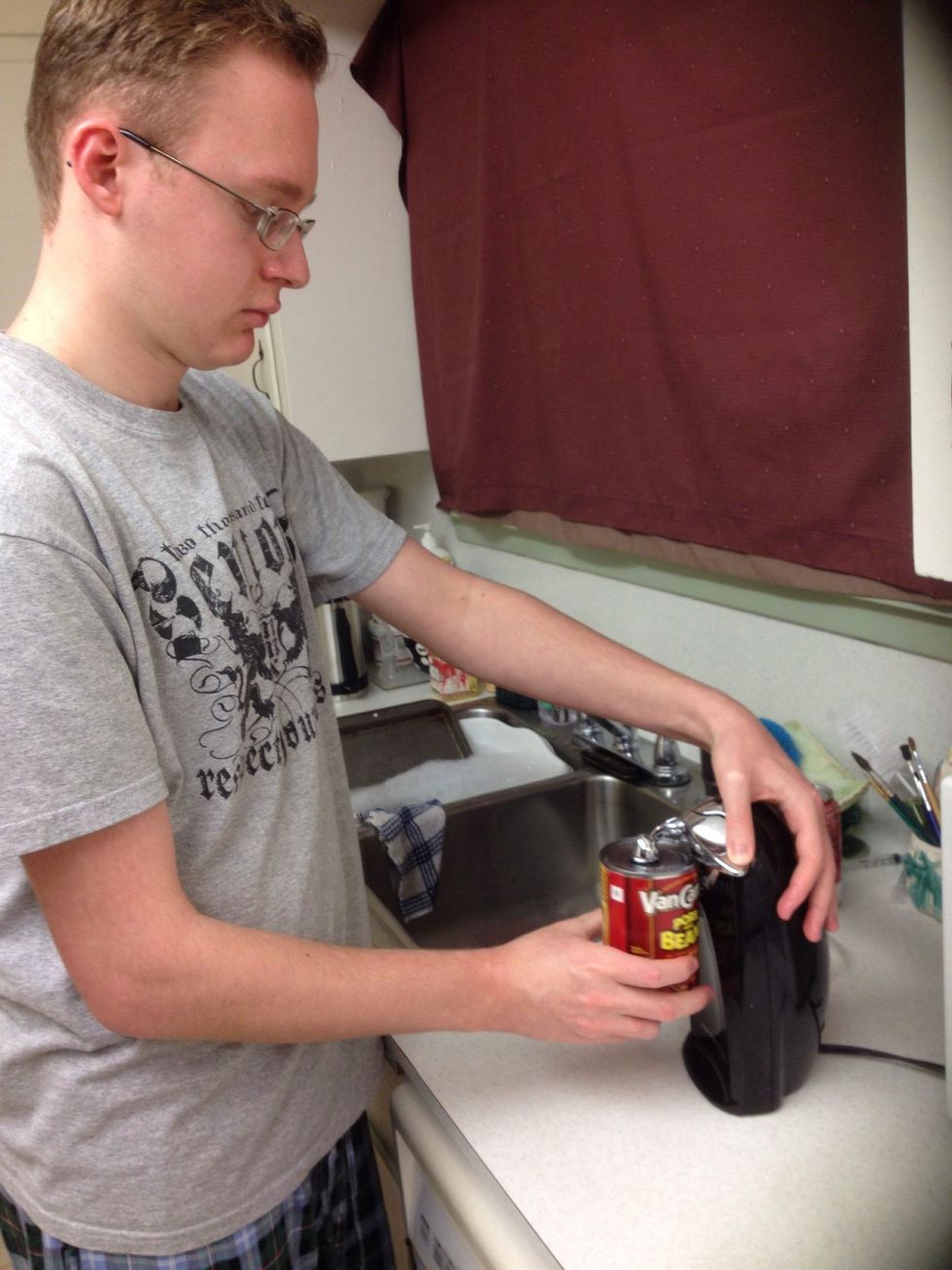 Open the two cans of beans using the can opener.