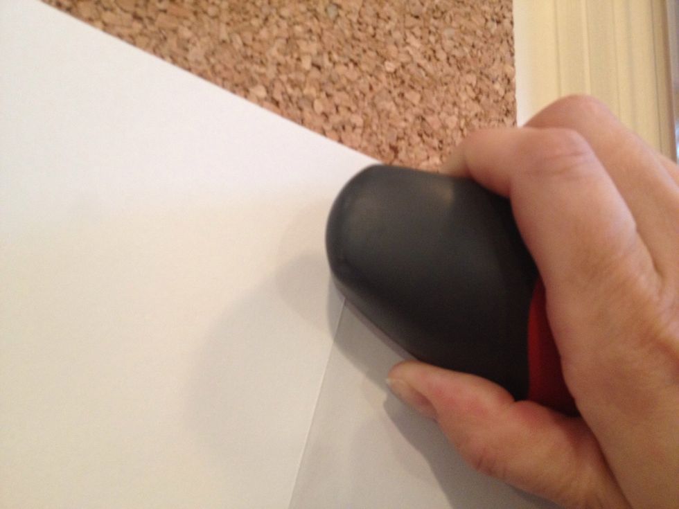 Open up the folded paper stack and lay the inside of it against the cork board. Line up the stapler with the fold and push a staple through.
