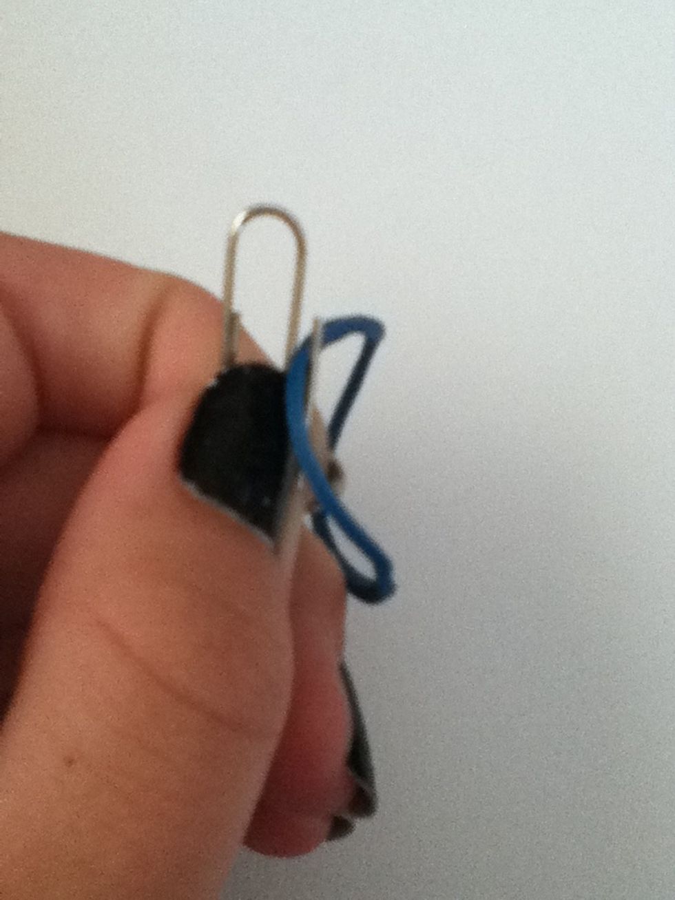 Open up the paper clip and slide a rubber band into it.