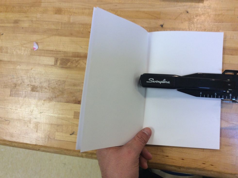 Open your booklet and slide it into the stapler, until the paper hits the silver metal measuring tab on the stapler. (The part where the staple goes in should be lined up with the fold on the booklet)