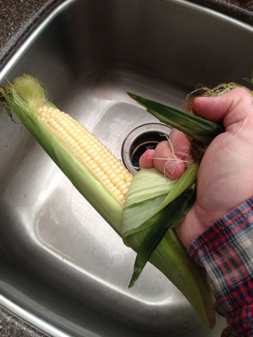 OR, you could peel back the husks, remove the silks leaving the husks attached, wash, put husks back over corn & soak in water for 1 hr. This allows grilling above the fire without too much char.
