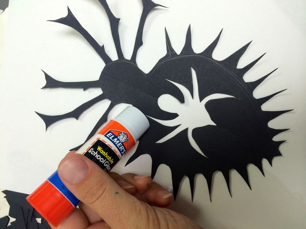 Over a piece if scrap paper, apply the glue stick to the black paper. Do this on the side with pencil marks.