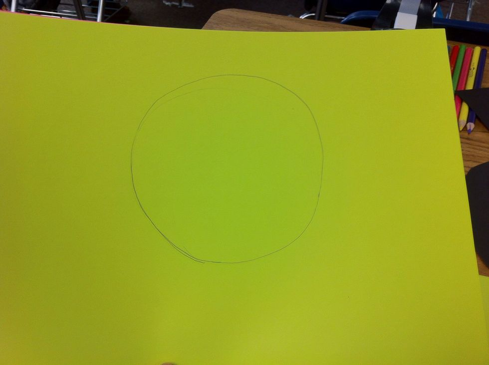Overlap the two different colored sheets of paper and draw another circle. A little bit smaller than the black circle.