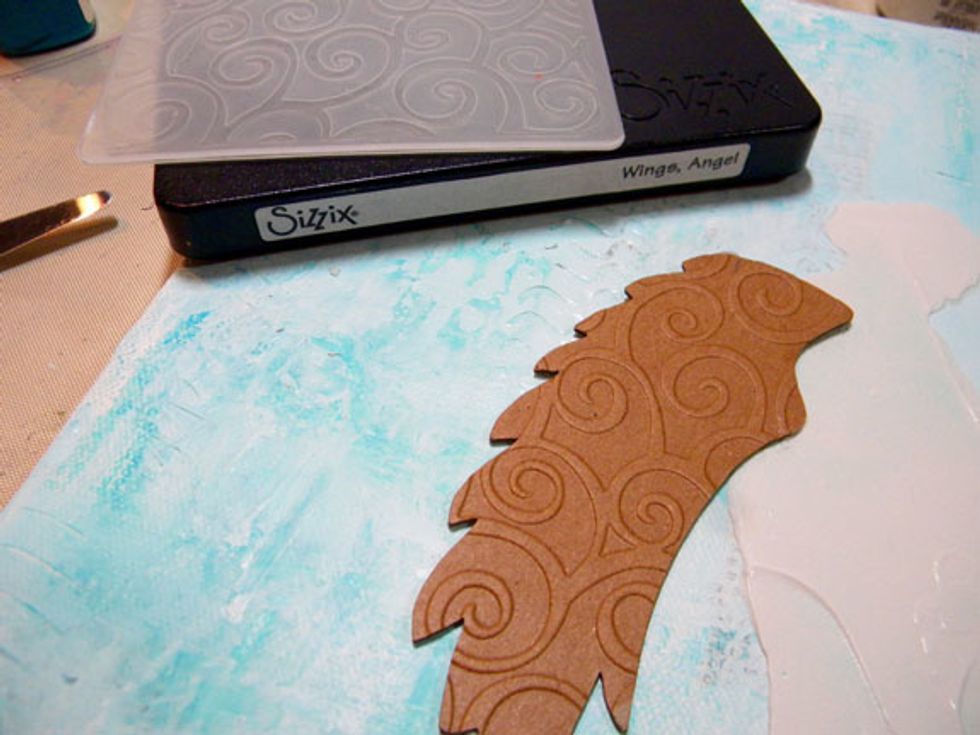 Overlap the wing with the silhouette stenciled onto the canvas, so the wing comes out of the back. Paint a coat of gesso on the wing.