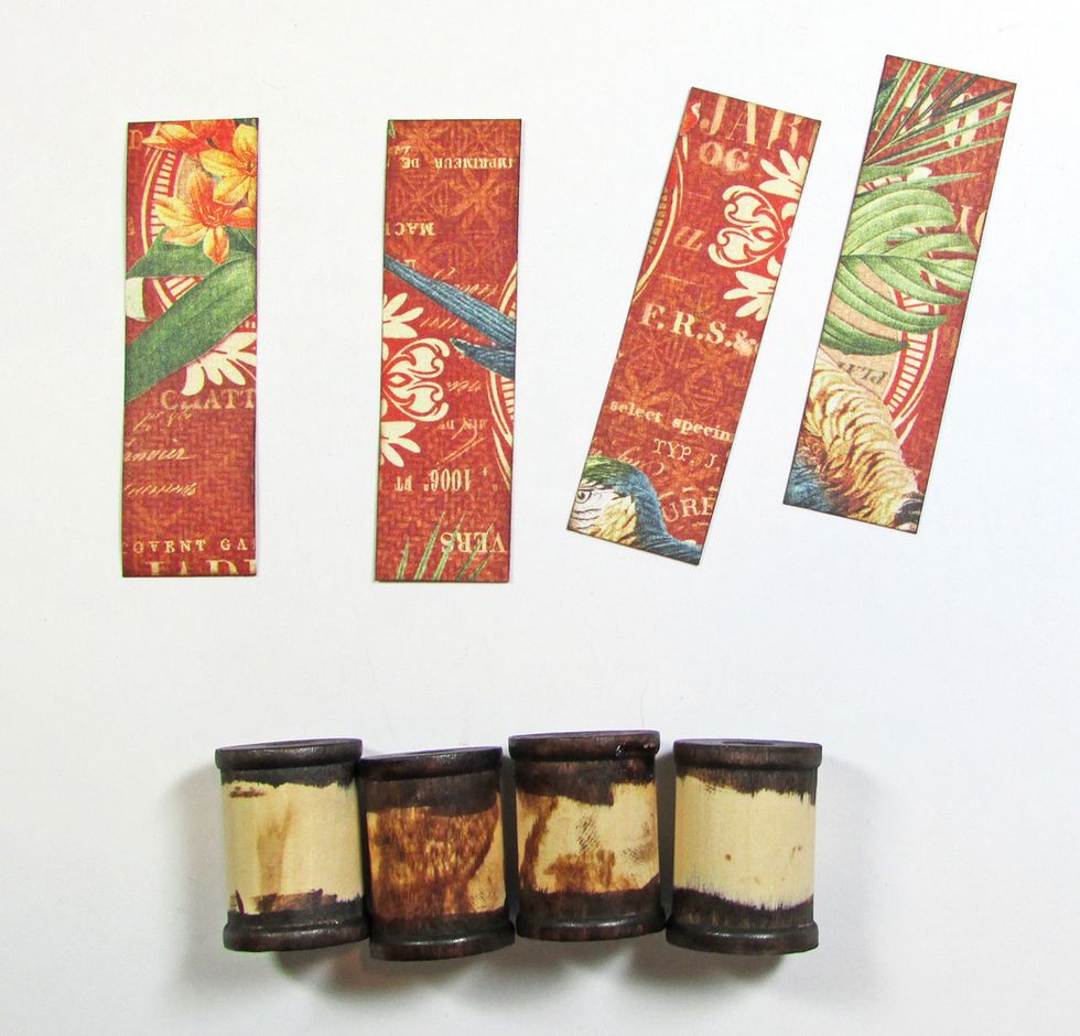 Paint or ink four wood spools. Trim four pieces of paper to wrap around the spools. Ink the edges of the paper with brown ink.