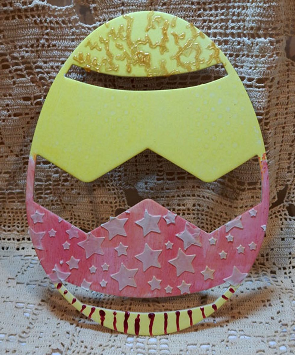 Paint part of the egg Mia Bella Sorbet. Add Stucco through the Stars stencil. Draw lines of Red Corvette Dimensional Crystals along the bottom edge.