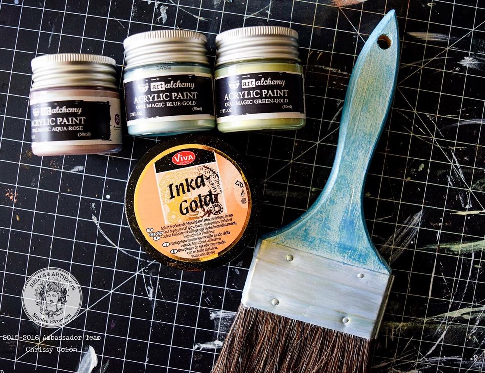 Paint the brush with gesso. Apply Finnabair paint in Blue-Gold all over. Go crazy with it! Dab Opal Green-Gold with finger and smear, When dry, use fingers and lightly rub on Inka Gold paint.
