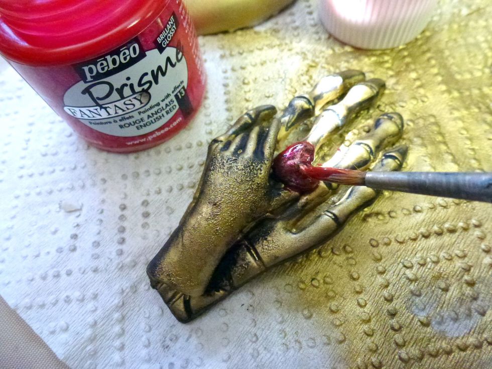 Paint the heart bead with red paint, and allow some of the paint to dribble down the hand so it appears as though the heart is bleeding.