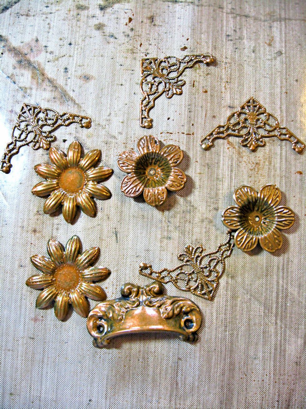Paint the metal embellishments with Antique Bronze Distress Paint.  Dry.  Tap the raised edges with a finger that you dip into Broken China paint.  Tap off the excess paint before applying to metal.