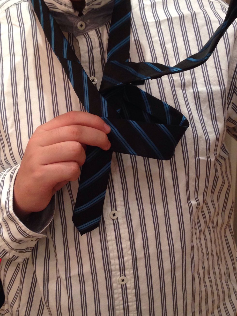 Pass the wide end under the left part of the loop around the neck.