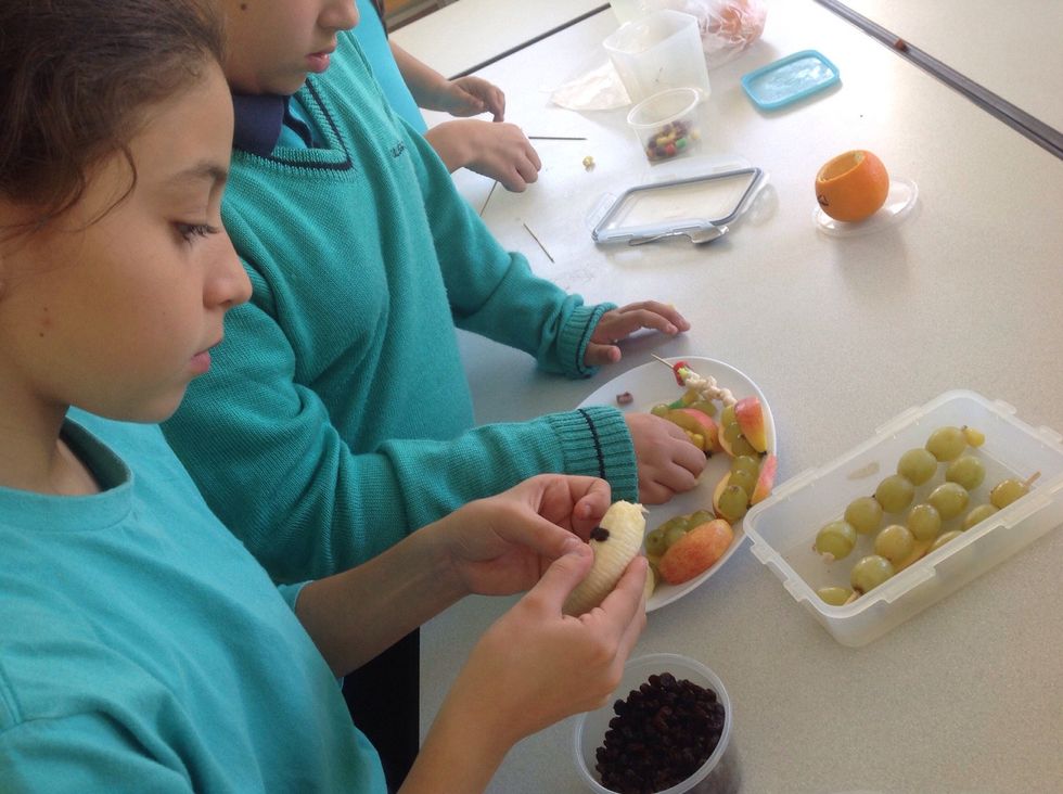 Peel a banana and cut it in half. Decorate the banana with raisins to form eyes and mouth.
