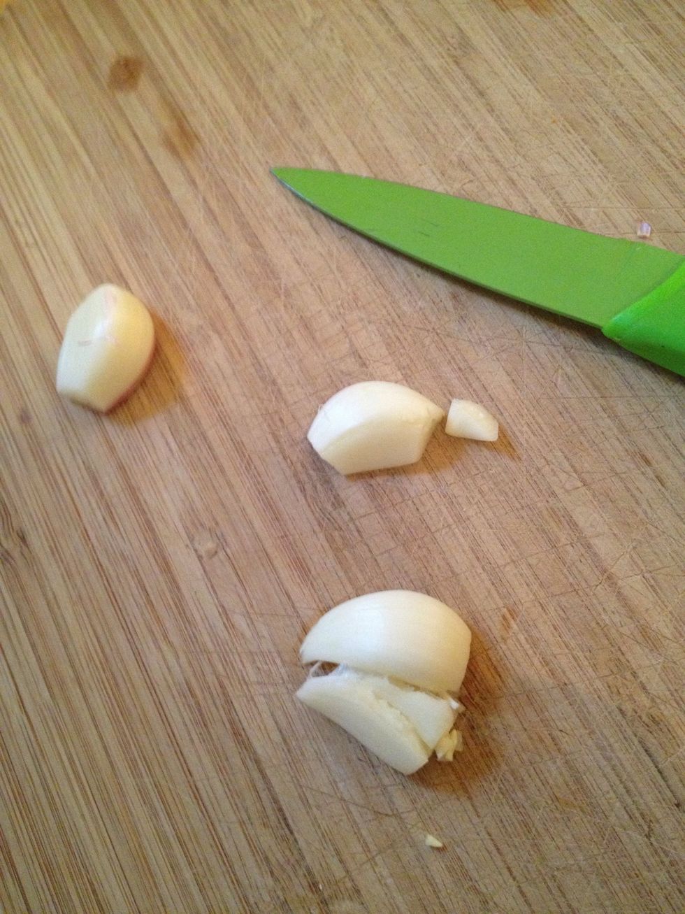 Peel and flatten three cloves of garlic and add to water