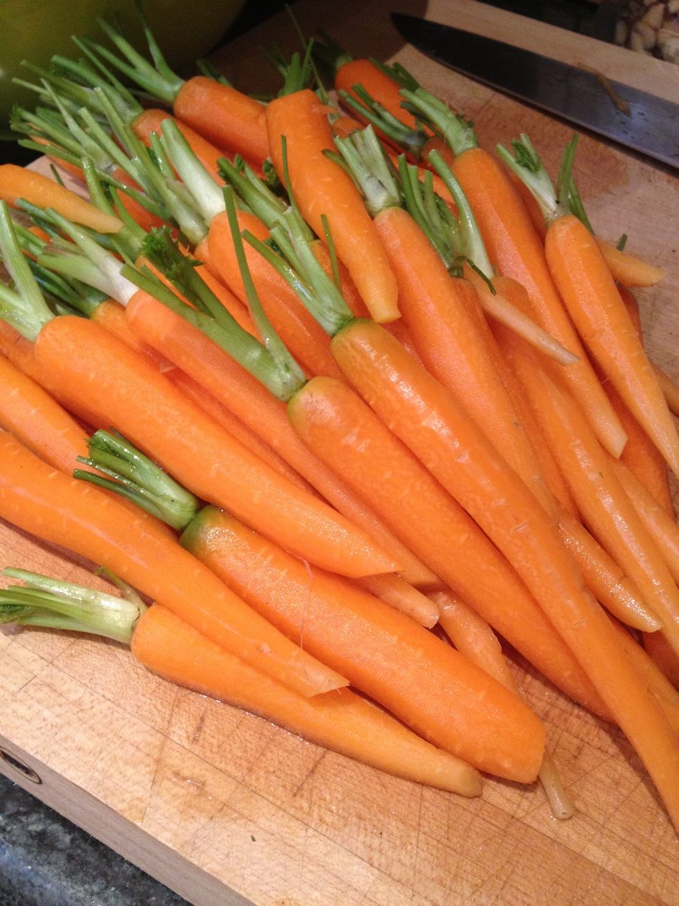 Peel and trim the baby carrots keeping 1/2 inch green top still attached. If you can only find large carrots (anything more then 1inch in diameter) then also slice them down the center.