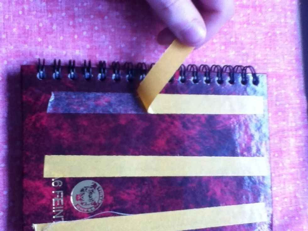 Peel off the sticky tape, and then press that side of the notebook down onto the fabric carefully.