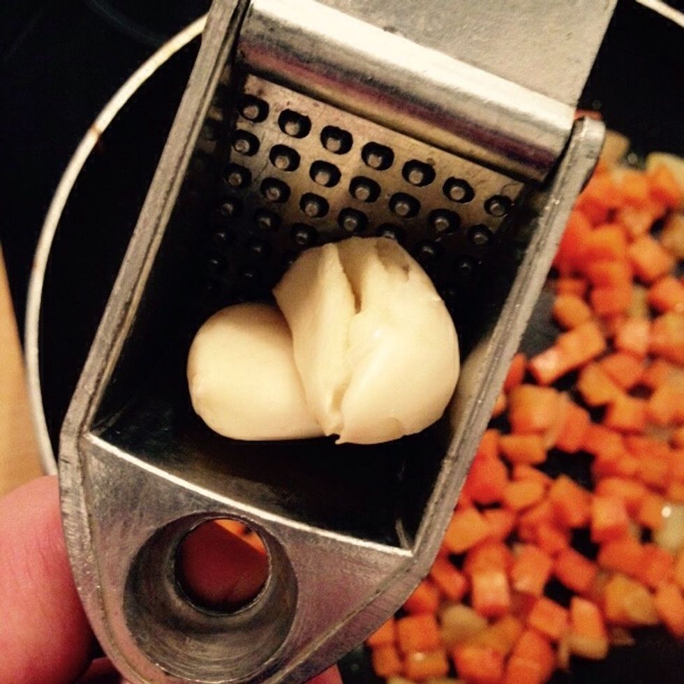 Peel the garlic cloves and crush them into the pan