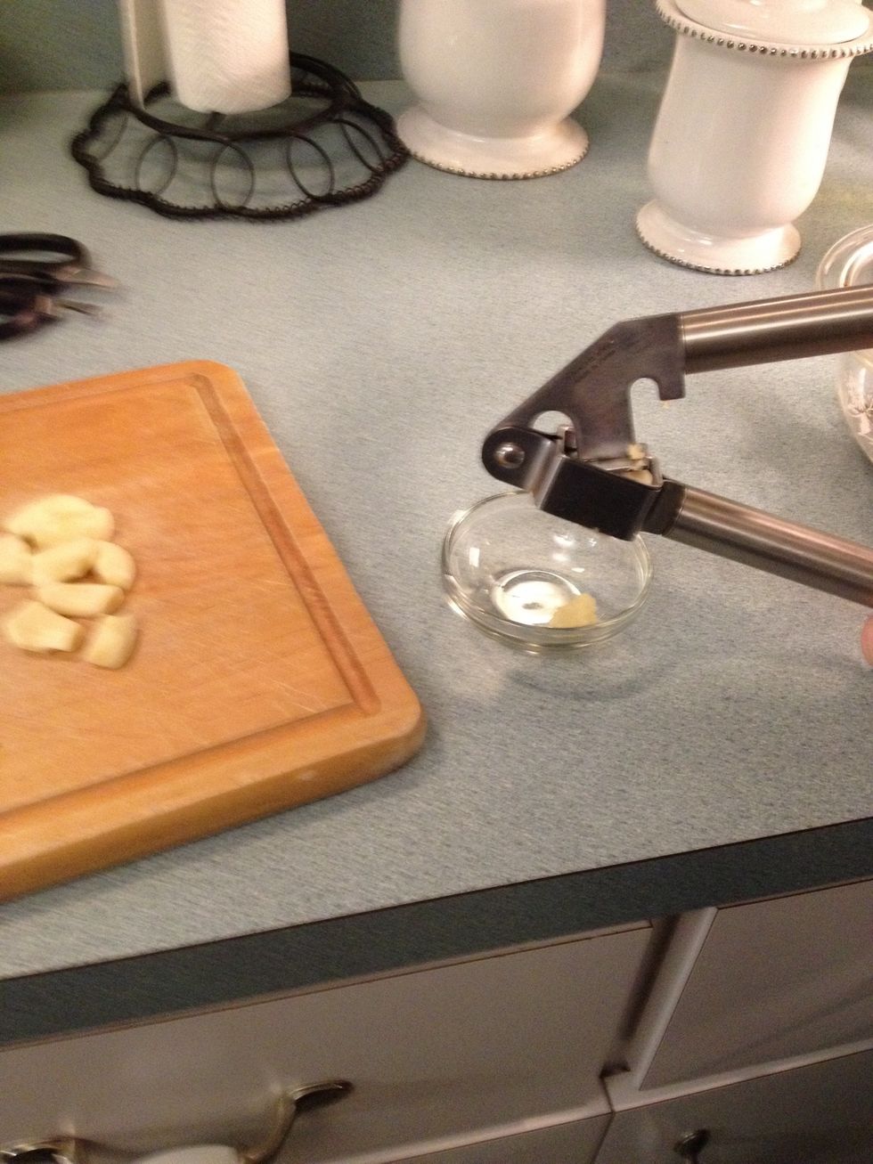 Peel the skin off of each garlic clove. Put each individual clove into the garlic press to mince.