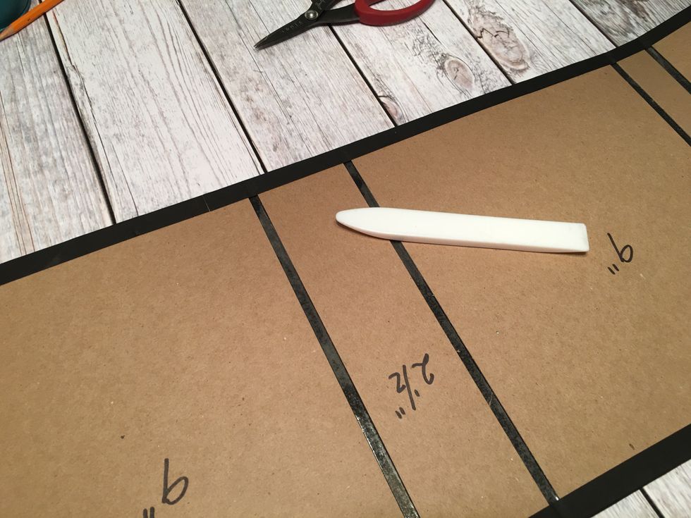 Peel the tape backing off the long edges first and use your bone folder to fold the card stock over on to the chipboard.