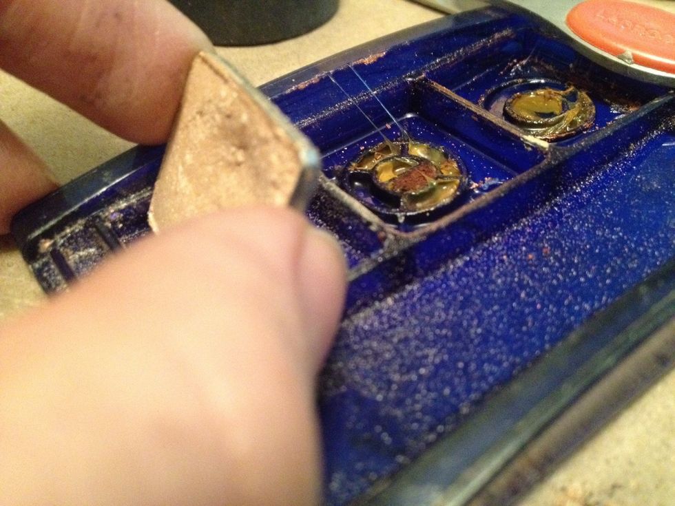 Photo of eyeshadow tin being pulled off of plastic base after glue has slightly melted.
