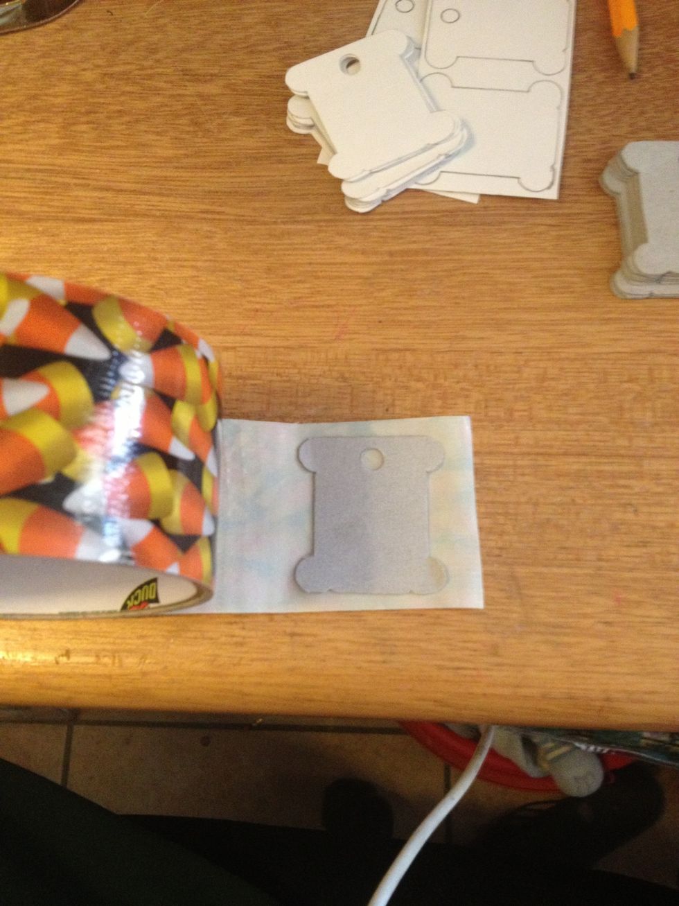 Pick out some duct tape and lay your bobbin on it. Completely cover the bobbin with tape.